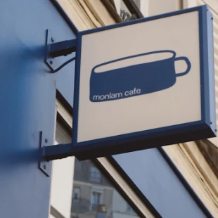 L’enseigne bleue de Monlam, avec la tasse de son logo