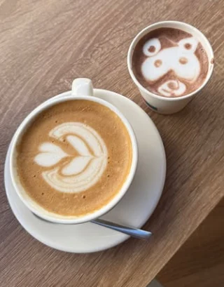 Un latte à la feuille et un chocolat chaud avec un ours dessiné dans la mousse